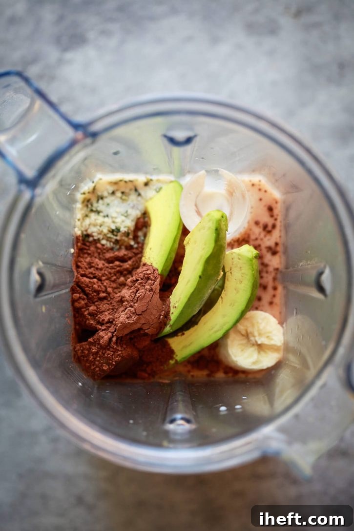 A Vitamix blender is filled with the ingredients for a healthy chocolate banana avocado smoothie. 