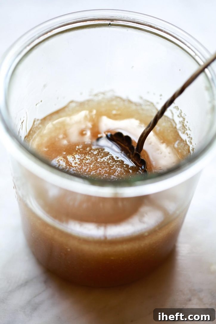 A close-up shot of the finished coconut sugar scrub in a jar, with a pristine white background. The scrub looks rich and textured, ready for use.