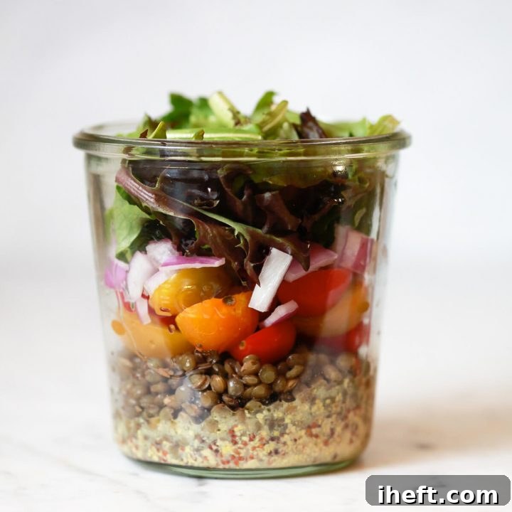 A layered mason jar salad recipe with lentils, tomatoes, onions, and lettuce.