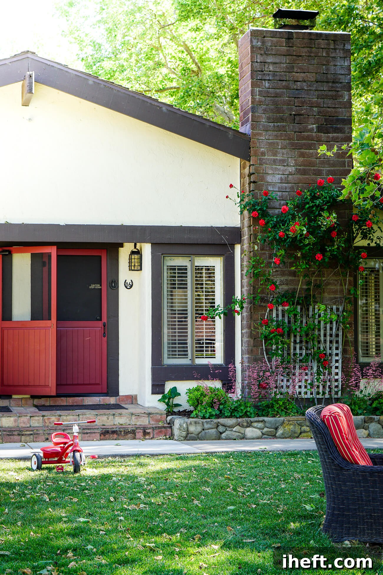 The front of a charming cottage with red doors at the Alisal Guest Ranch in Solvang, CA. A red tricycle sits in the grass in front of the cottage. A family-friendly luxury vacation. 
