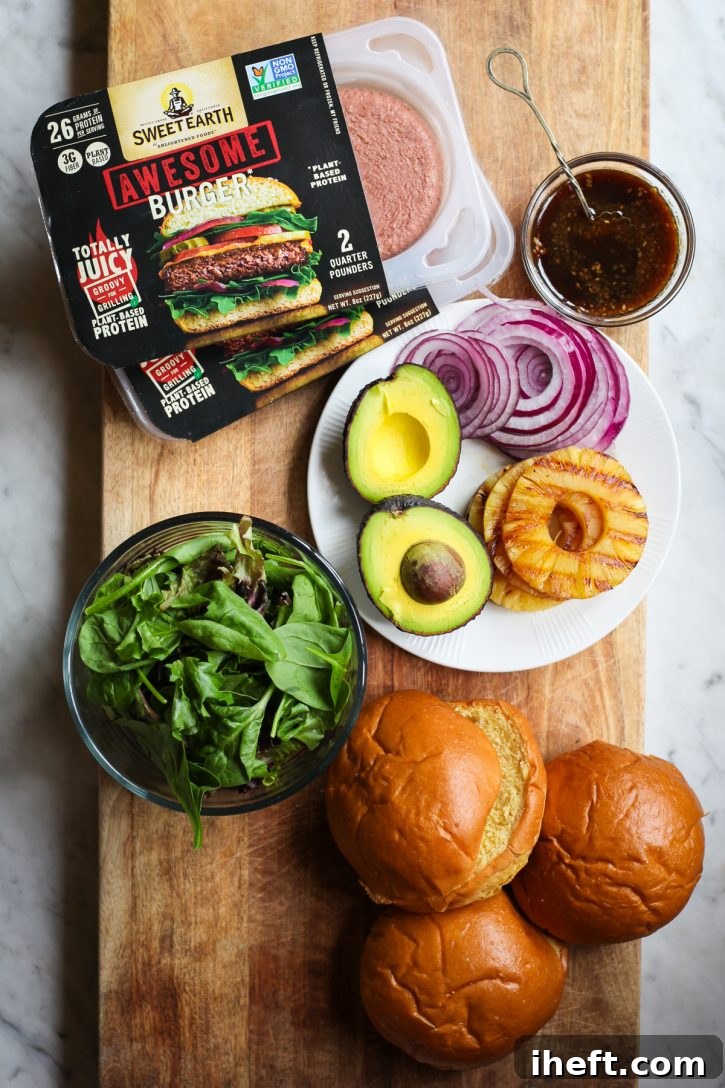 Plant Based vegan hamburger patties, toppings, and buns sit on a cutting board alongside a small bowl of teriyaki sauce.