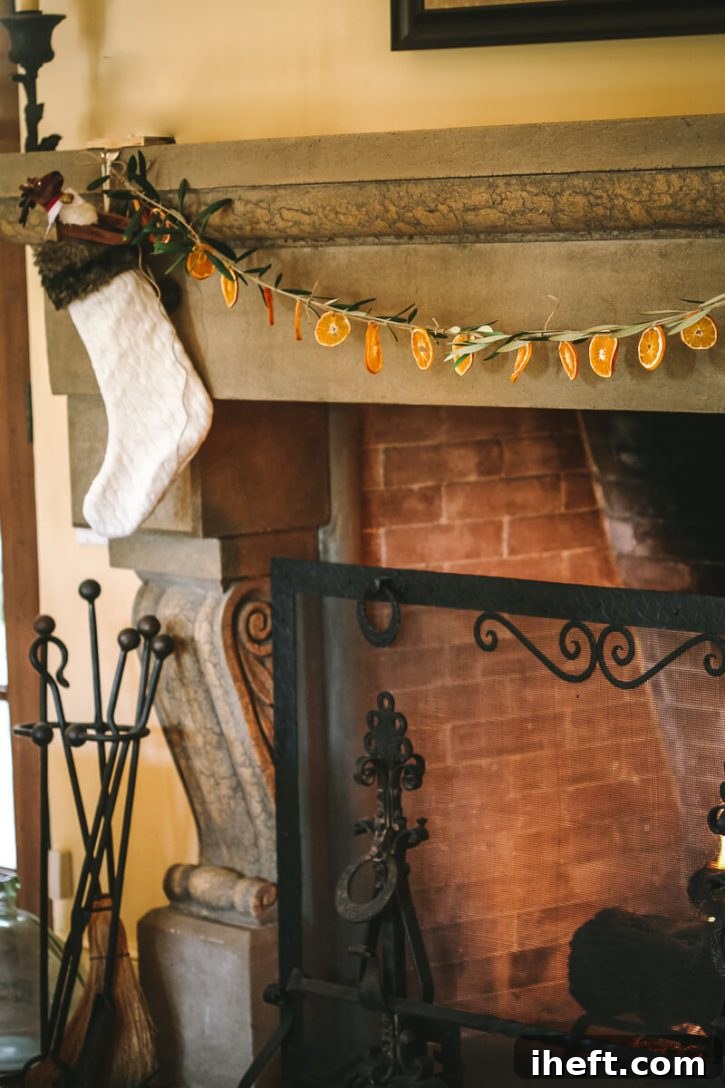 A beautiful homemade garland of dried orange slices and olive branches is hung over a large stone fireplace.