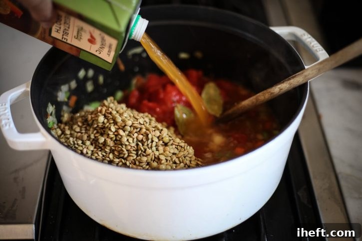 Green/Brown lentils and vegetable broth are added to a soup pot. 