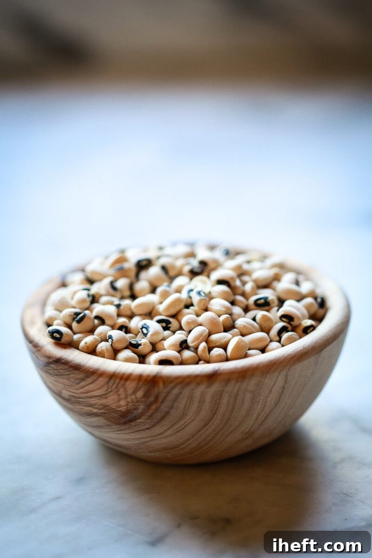 A small, rustic olive wood bowl filled with approximately one cup of dried black eyed peas, illustrating the raw ingredient. 