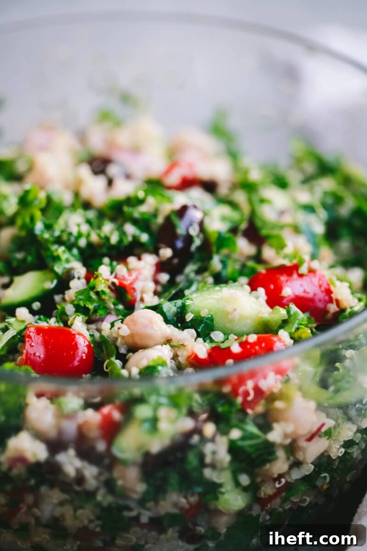 A vibrant close-up photo of a healthy Mediterranean quinoa salad, packed with fresh shredded kale, plump chickpeas, crisp cucumber slices, juicy cherry tomatoes, Kalamata olives, and a sprinkle of fresh herbs.