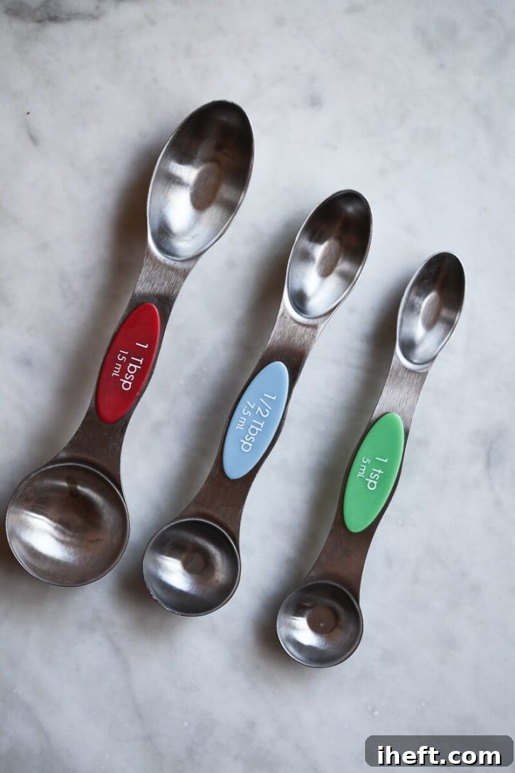 A teaspoon, half teaspoon, and tablespoon sit on a counter to show the size difference. 