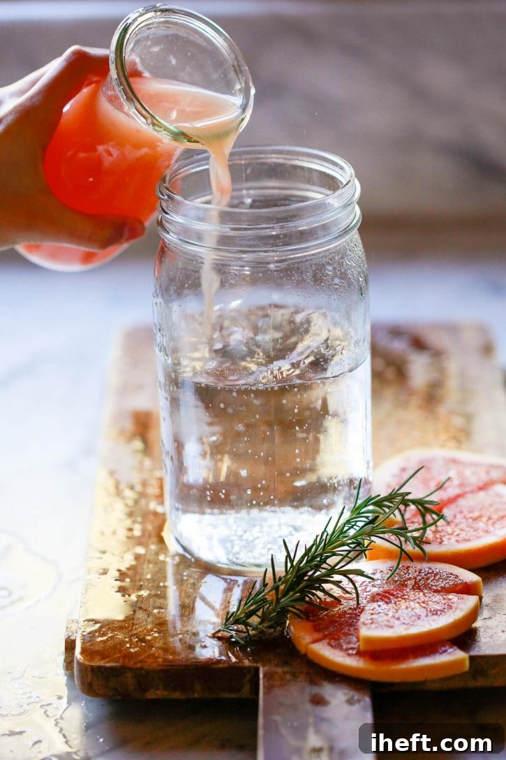 Fresh grapefruit juice is poured into a mason jar filled with sparkling water to make sugar free grapefruit soda, illustrating the easy mixing process.