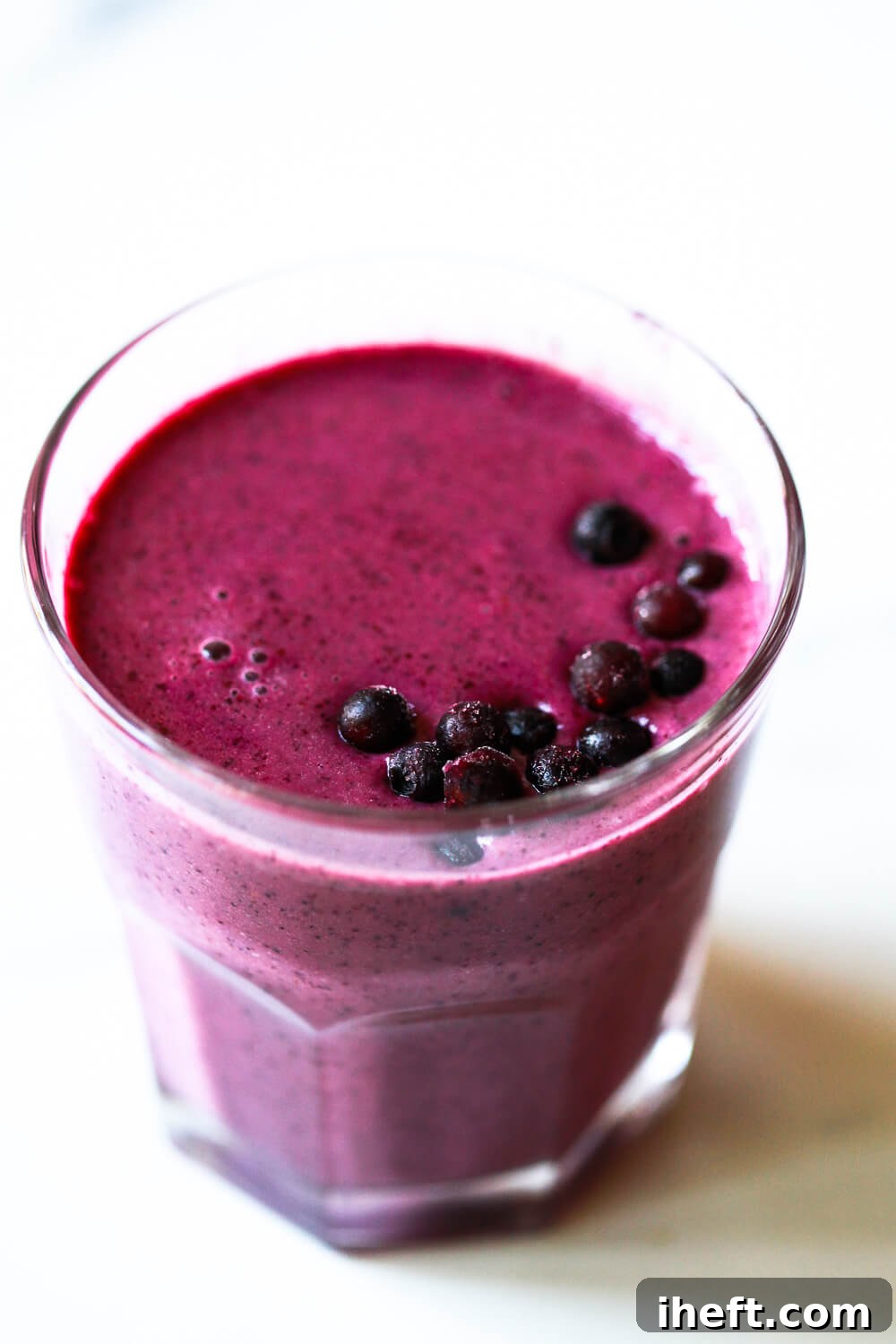 A beautiful purple blueberry pomegranate smoothie in a glass.