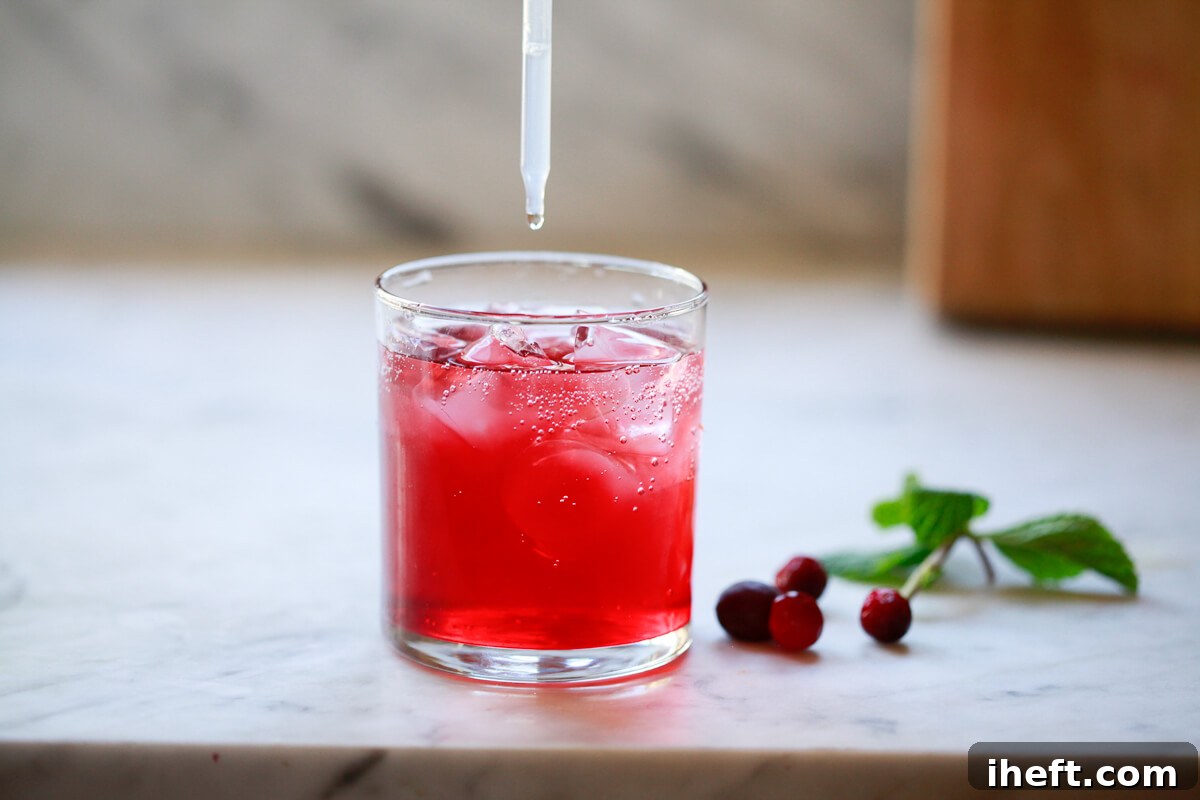 A few drops of liquid stevia are being added to a glass of cranberry detox water to sweeten it.
