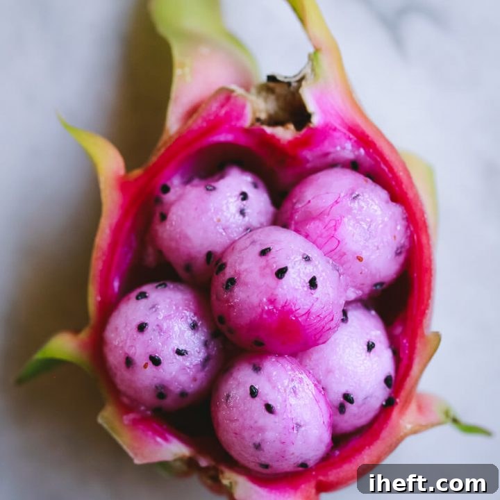 Half a dragon fruit filled with perfectly cut dragon fruit balls, ready to be enjoyed.