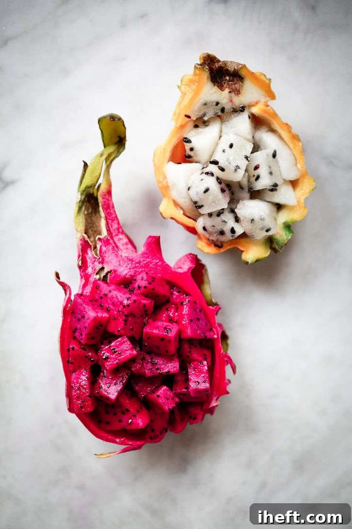 Half of a yellow-skinned and half of a red-skinned dragon fruit pitaya, both expertly cut into cubes and elegantly served back in their original skins.