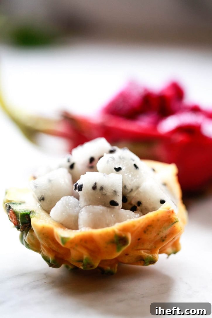 Close up photograph of half a yellow dragon fruit with creamy white flesh and slightly larger black seeds, precisely cut into cubes.