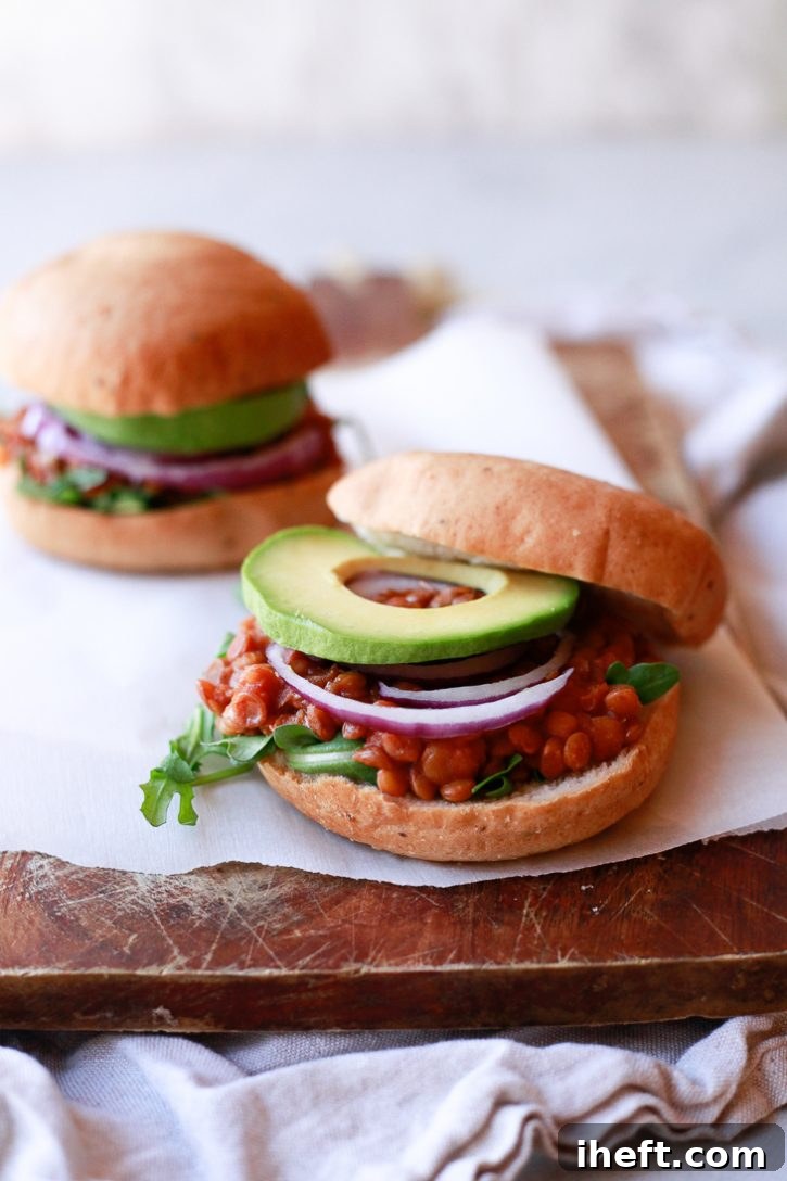 Vegan lentil sloppy joes on hamburger buns with onions and avocado rings. 