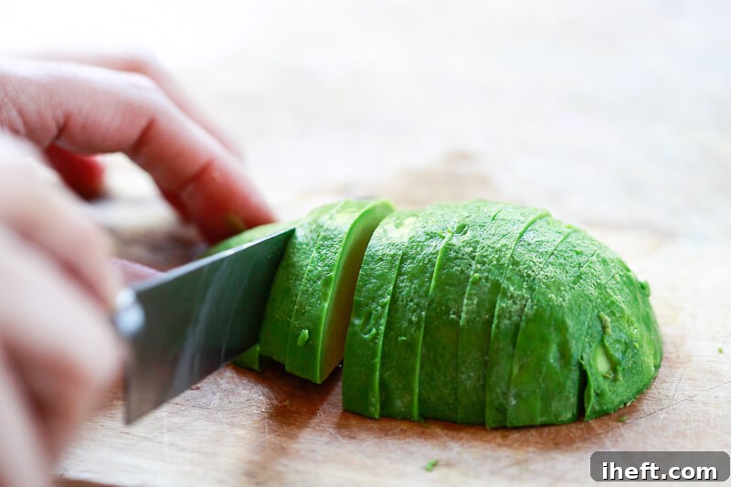Half a peeled avocado is cut into slices.
