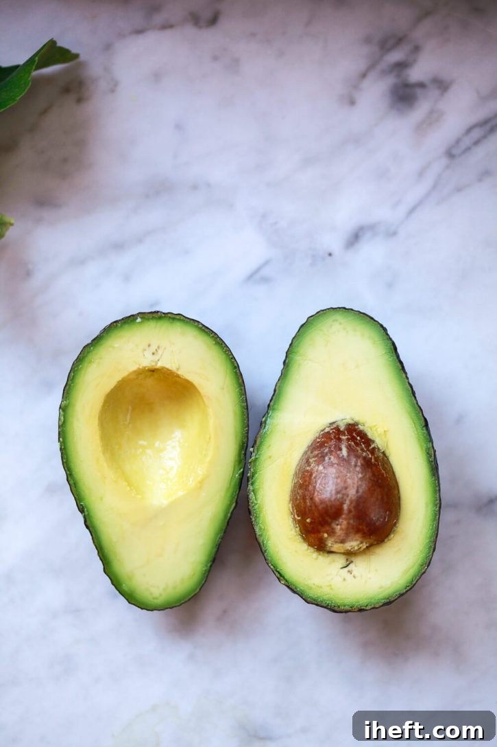 Avocado halves on a marble countertop. 