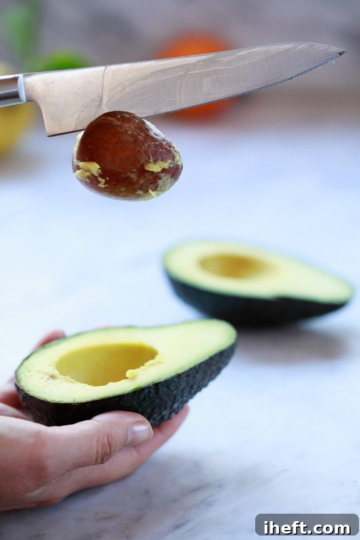 An avocado seed is removed from half of an avocado. 
