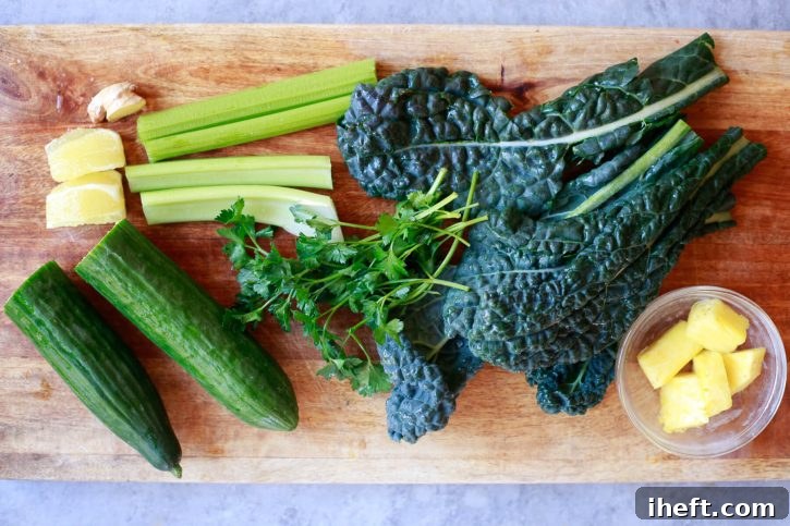 Kale, cucumber, celery, lemon, parsley, ginger, and pineapple on a cutting board before being juiced. 