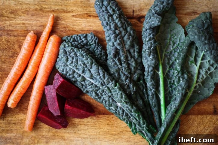 Ready for healthy juicing, carrots, beetroot, and kale on a cutting board. 