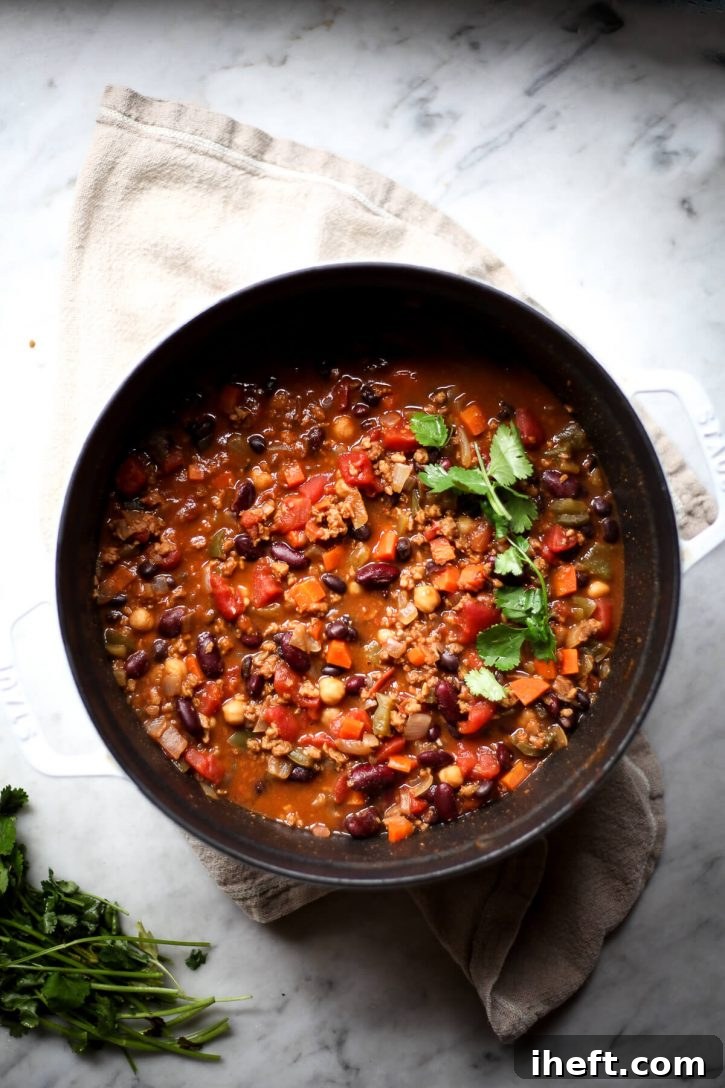 An overhead shot of a pot of hearty vegan bean chili, garnished generously with fresh cilantro, invitingly warm and flavorful.