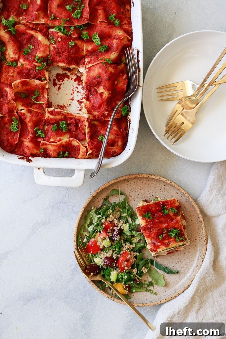 A mouth-watering photo of a generous slice of vegan lasagna, rich with creamy almond-based ricotta and layers of fresh vegetables, served alongside a crisp green salad.