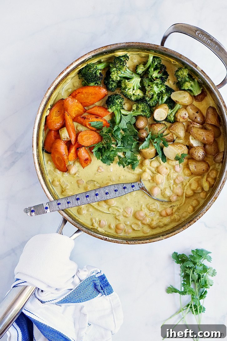 An inviting pan filled with vibrant yellow chickpea curry, generously topped with perfectly roasted broccoli, carrots, and potatoes, highlighting it as an easy and healthy vegan dinner recipe for beginners.