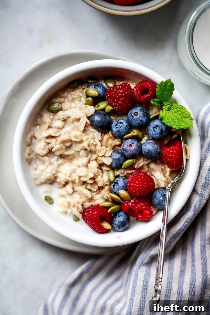 A beautifully presented bowl of high-protein oatmeal, generously topped with vibrant blueberries, luscious raspberries, and crunchy pumpkin seeds, ready to be enjoyed.