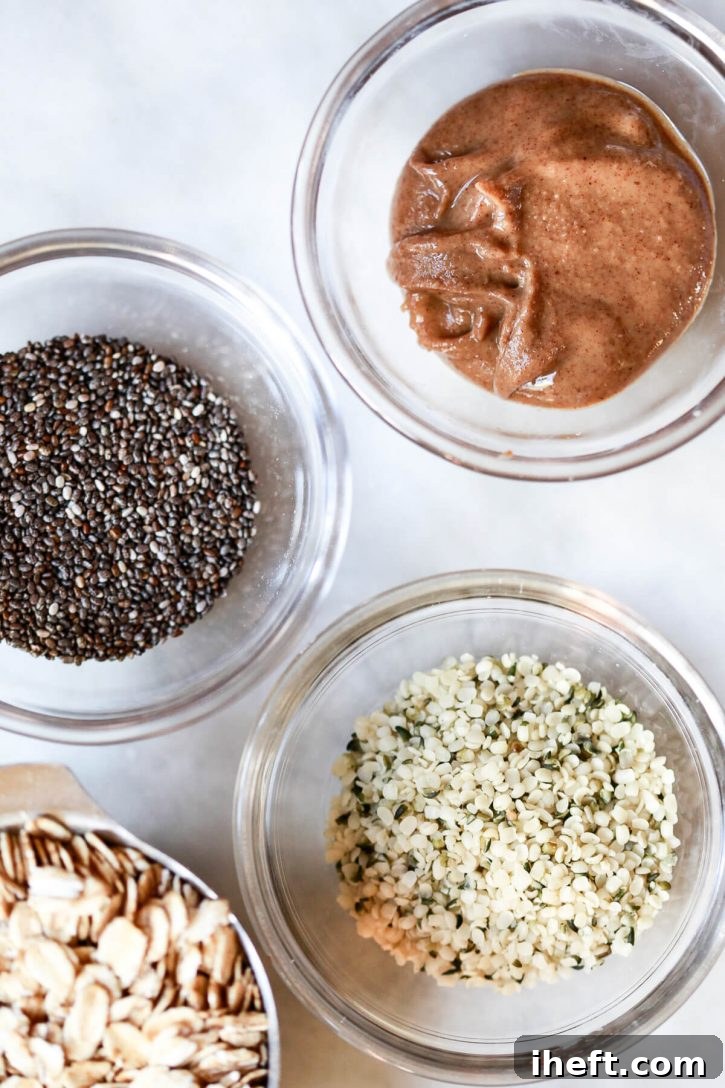 Three small, inviting bowls sit on a kitchen counter, showcasing various protein-boosting ingredients: one filled with chia seeds, another with hemp seeds, and a third with creamy almond butter, all ready to be added to oatmeal.