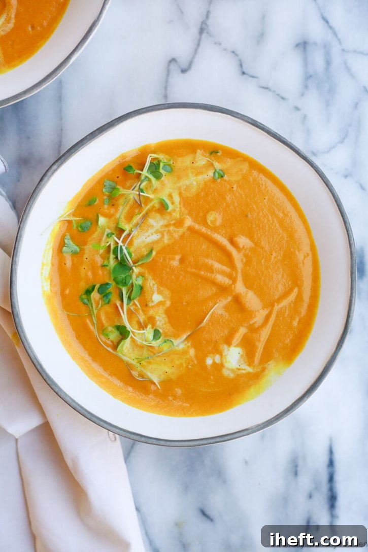 A cozy bowl of creamy carrot ginger soup, beautifully garnished with fresh microgreens and a delicate swirl of coconut milk, hinting at its vibrant flavors.