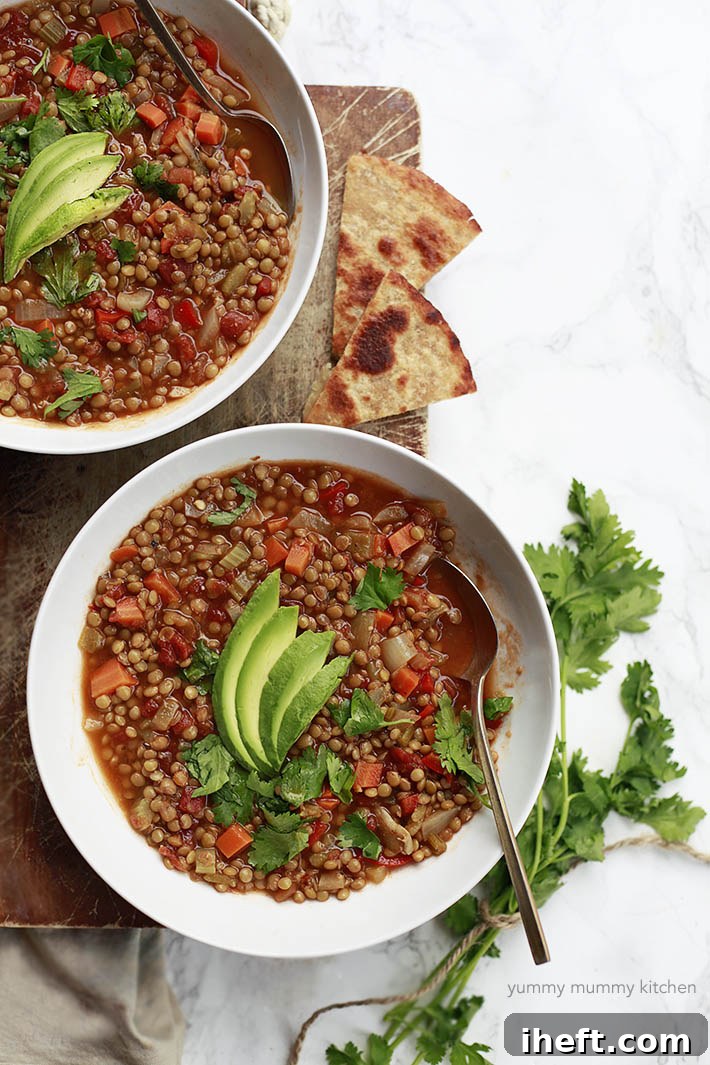 Two enticing bowls filled with Mexican green lentil soup, generously topped with creamy avocado slices and fresh cilantro, promising a flavorful experience.