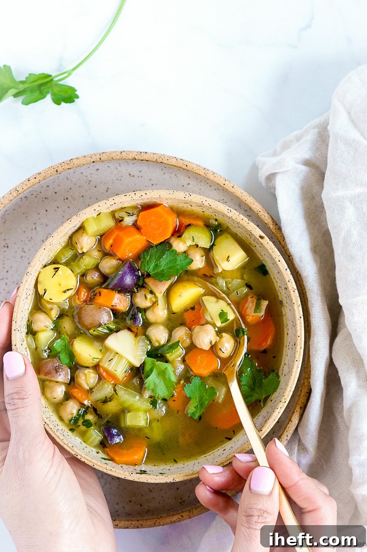 A comforting pair of hands cradling a bowl of wholesome chickpea vegetable soup, inviting warmth and deliciousness.