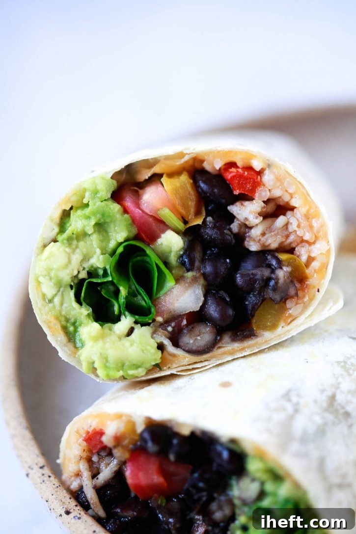 A mouth-watering close-up photo of a vibrant vegan burrito, generously filled with freshly cooked black beans, fluffy Spanish rice, crisp lettuce, tangy salsa, and creamy guacamole.