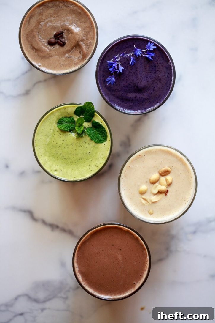 A vibrant display of five different protein shake recipes, including coffee, berry, peanut butter, chocolate, and mint chip, beautifully arranged on a marble kitchen counter.