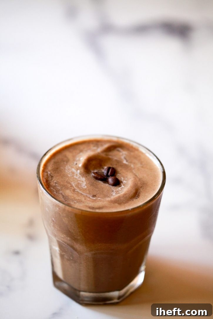 A close-up shot of a rich coffee protein shake, artfully garnished with three whole coffee beans on top, emphasizing its invigorating flavor.
