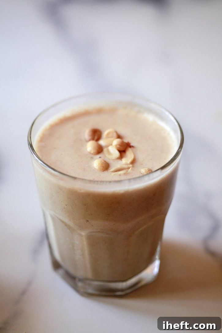 A close-up shot of a creamy peanut butter protein shake, garnished with a sprinkle of chopped peanuts, highlighting its rich and nutty flavor.