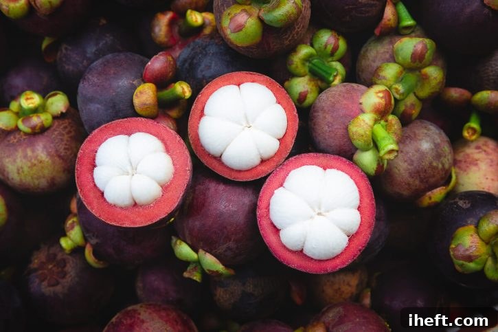 Photograph of ripe purple mangosteen with three cut in half to reveal the inside. A rare exotic fruit. 