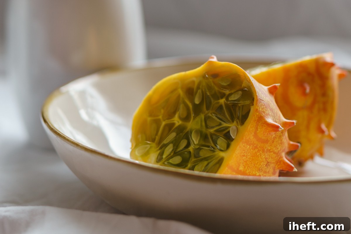Halves of horned melon in a white bowl. A very exotic fruit with spiky orange skin and green jelly fruit. 