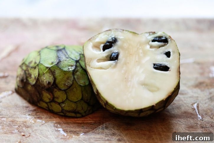 Half a Cherimoya sits on a cutting board. This is a delicious exotic fruit. 