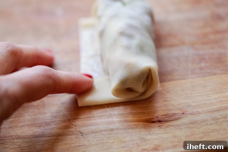 An egg roll wrapper is rolled around filling. 