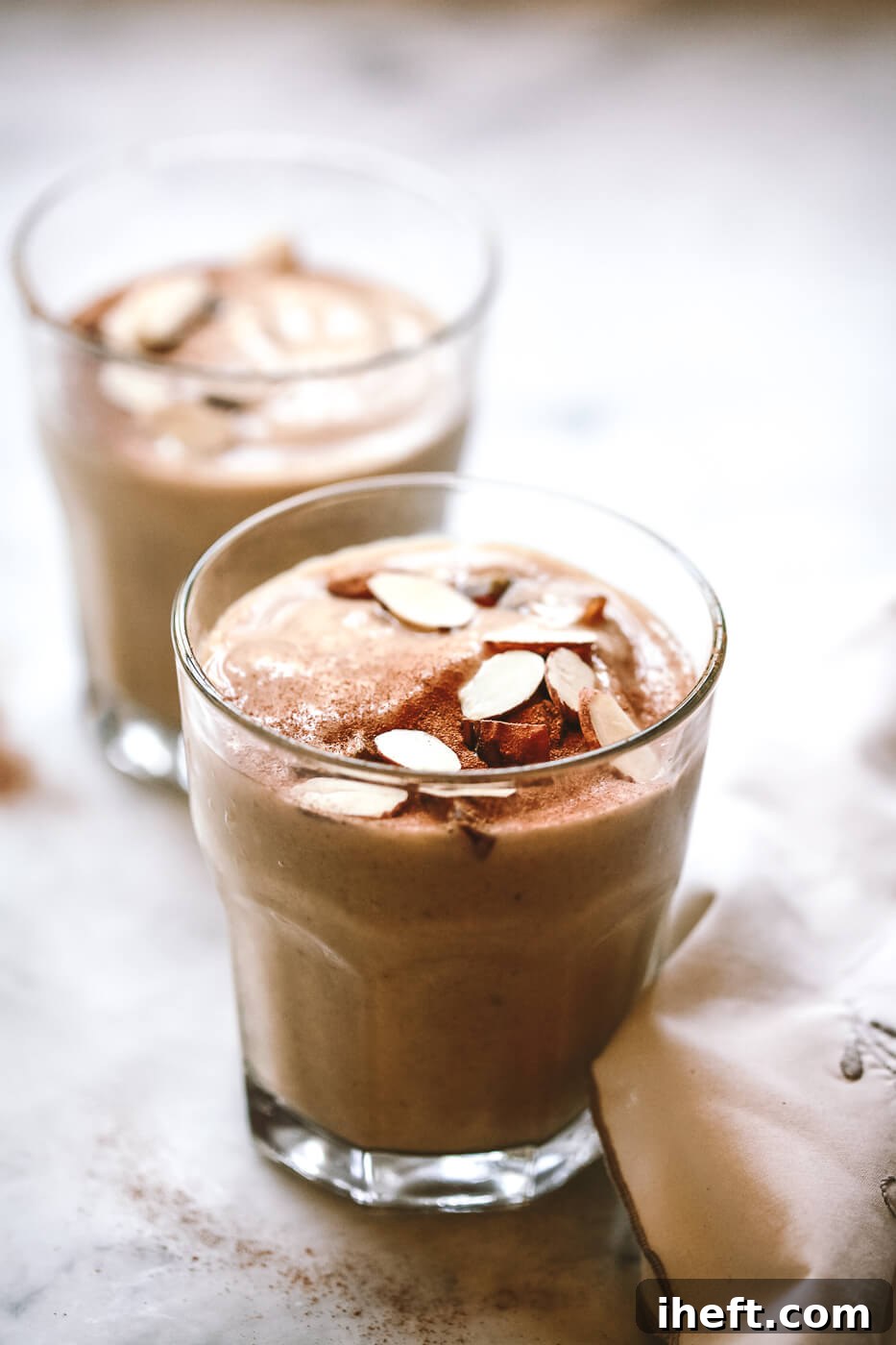 close up photo of a healthy date shake topped with slivered almonds and medjool dates