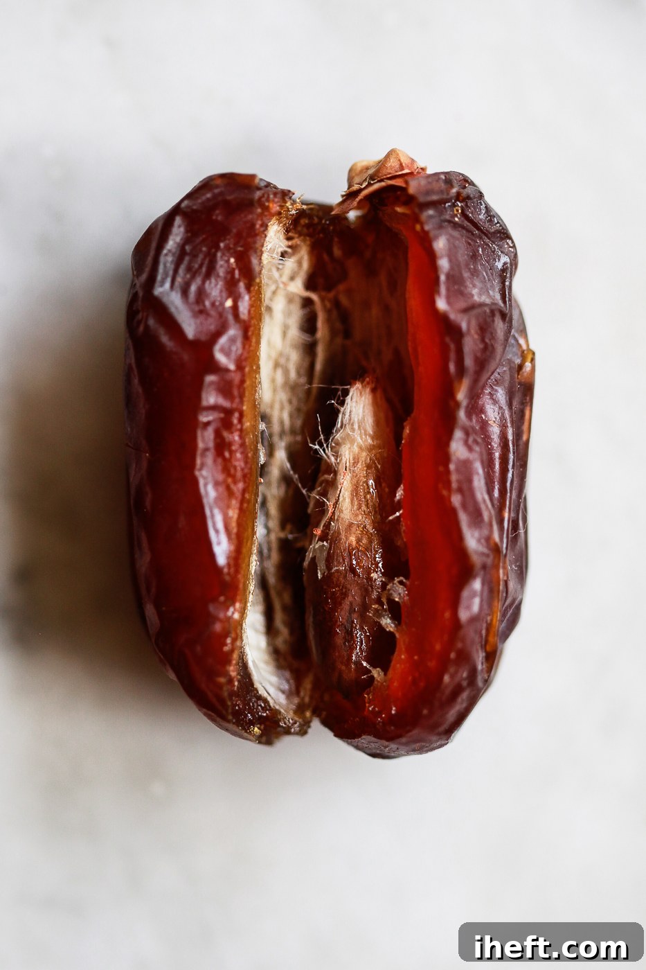 A macro photo of one Medjool date cut open to reveal the pit. 