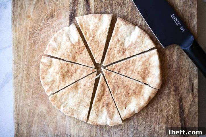 A piece of round pita bread is cut into eight pieces on a cutting board.