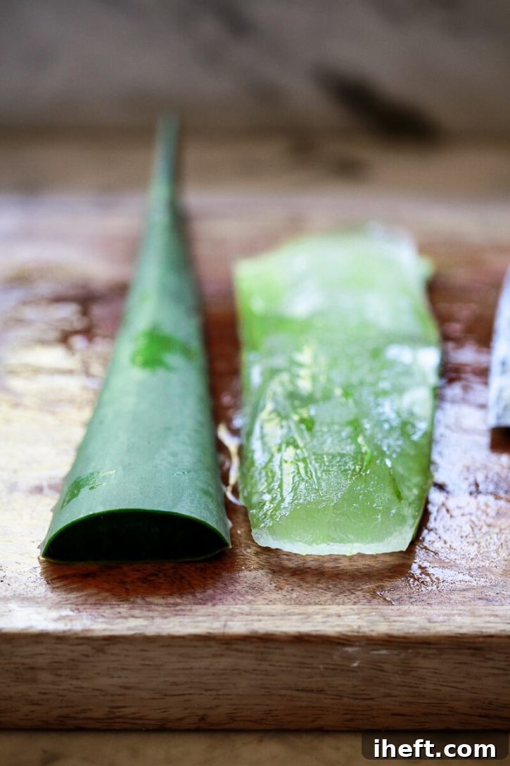 A large aloe vera leaf is shown in the process of being carefully peeled, progressively revealing the translucent, gelatinous inner aloe vera gel. This step is crucial for preparing the plant for use in homemade remedies or beverages.
