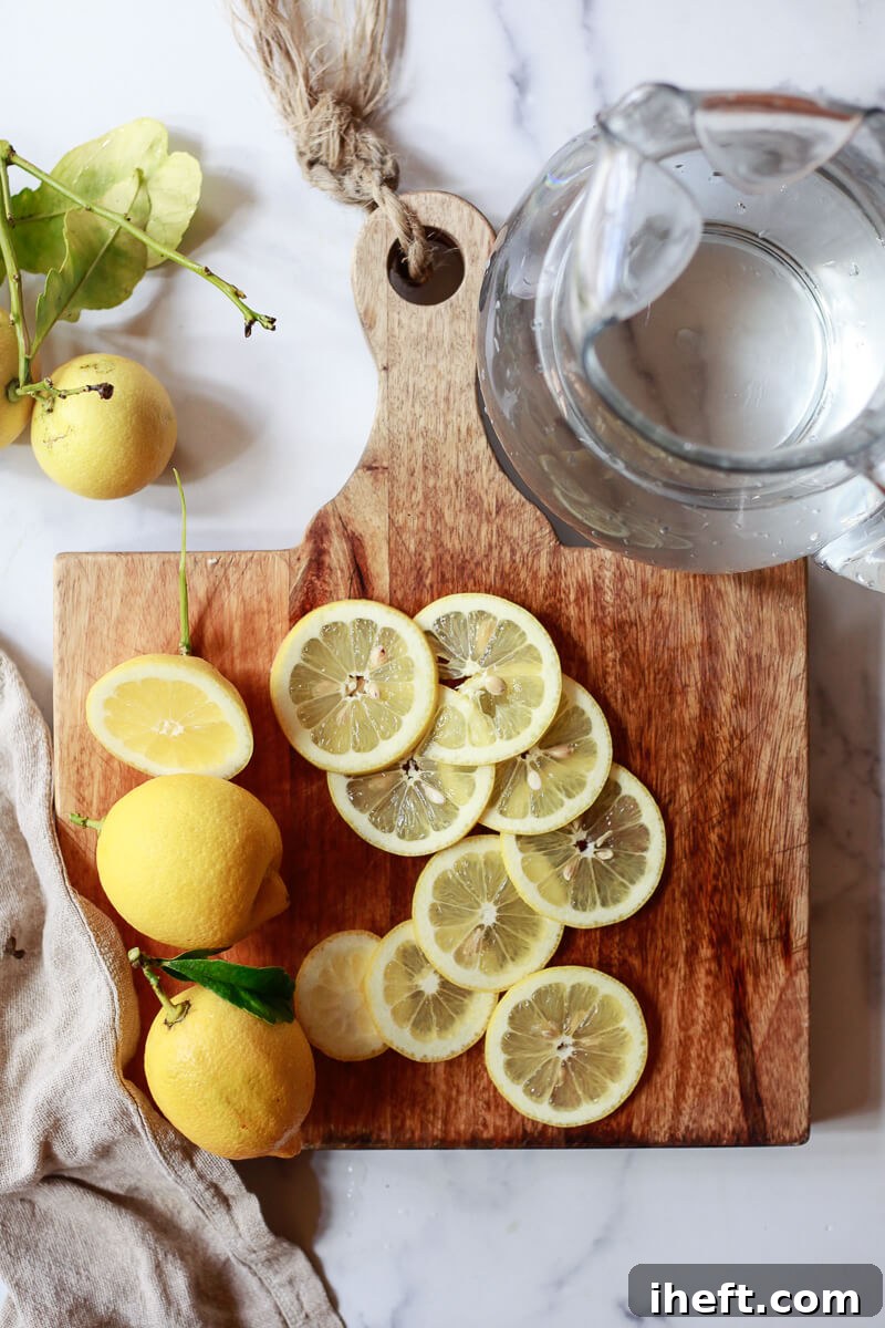 A cutting board topped with sliced lemons sits next to a pitcher of water.