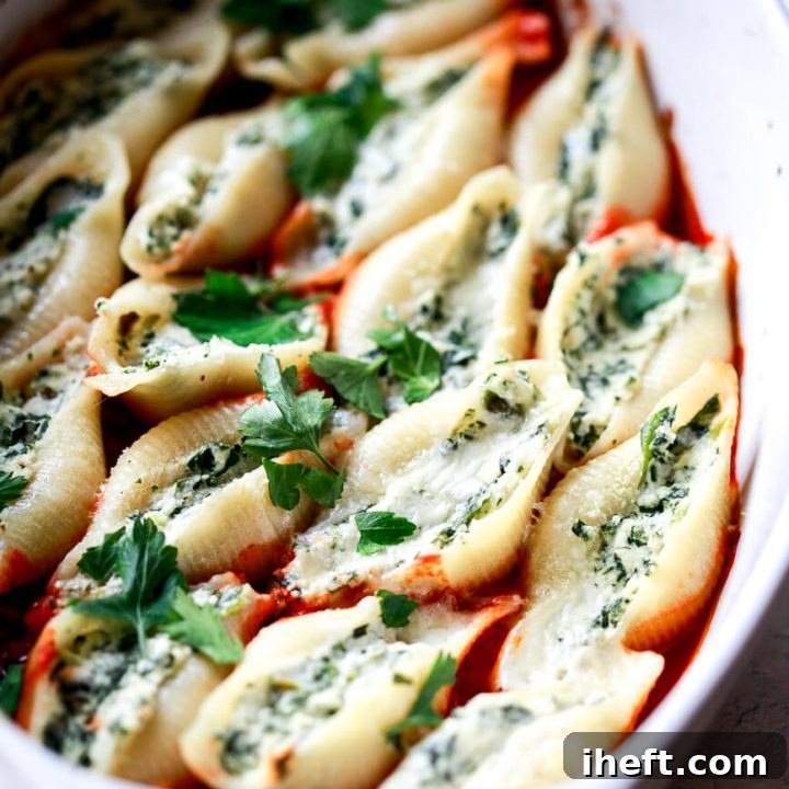 A white casserole dish filled with ricotta and spinach stuffed jumbo shell pasta.
