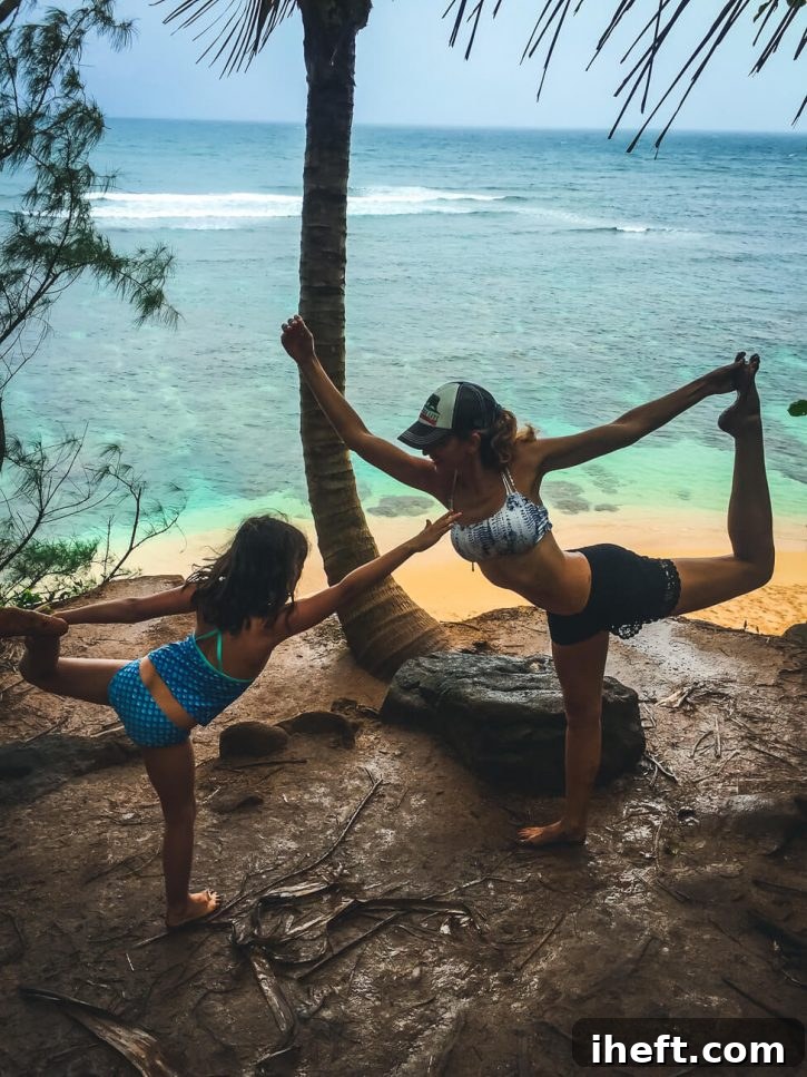 A mother and daughter gracefully performing dancer's pose barefoot on a lush Hawaiian landscape, symbolizing grounding and connection to the earth. 