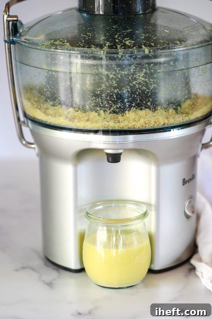 A high-performance Breville juicer efficiently extracts fresh ginger juice into a small, clear glass jar, demonstrating the process of juicing ginger with a specialized appliance.
