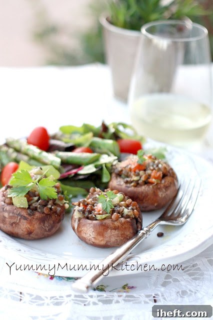 Smaller, appetizer-sized Portobello mushrooms, expertly stuffed with a savory lentil and vegetable mix, artfully arranged on a plate outdoors, suggesting a delightful al fresco dining experience.