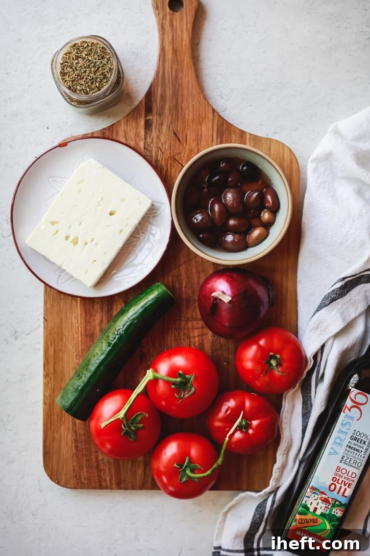 A vibrant selection of fresh ingredients for traditional Greek salad artfully arranged on a wooden cutting board, including ripe tomatoes, crisp cucumber, thinly sliced red onion, dark Kalamata olives, a block of creamy feta cheese, and dried Greek oregano.