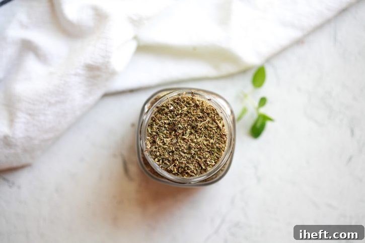 An intimate overhead shot of dried Greek oregano, a crucial herb, presented in a small bowl, showcasing its delicate, aromatic leaves.