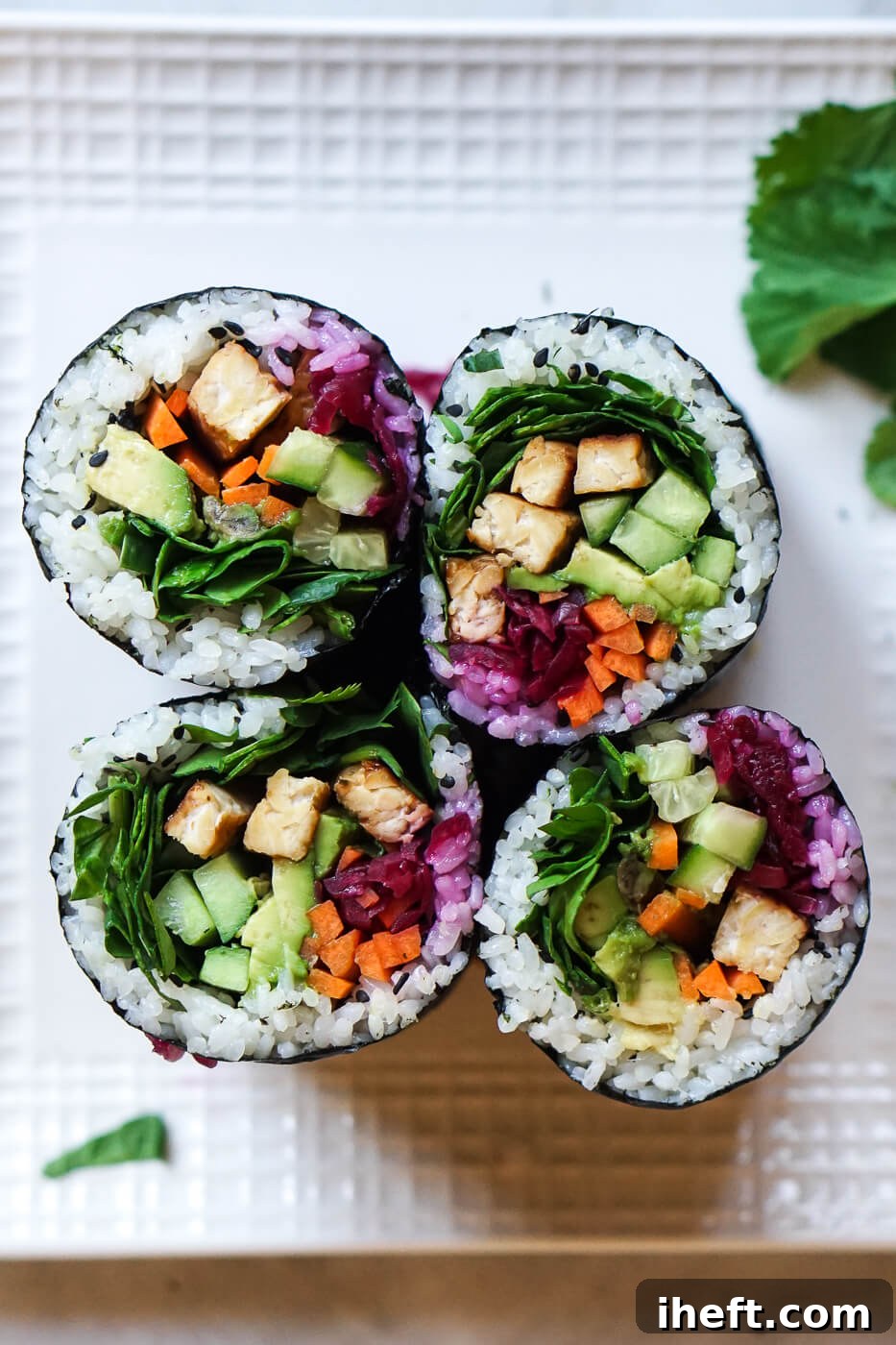 An overhead photo of 4 sushi burritos filled with tempeh, cucumber, carrots, avocado, and more.